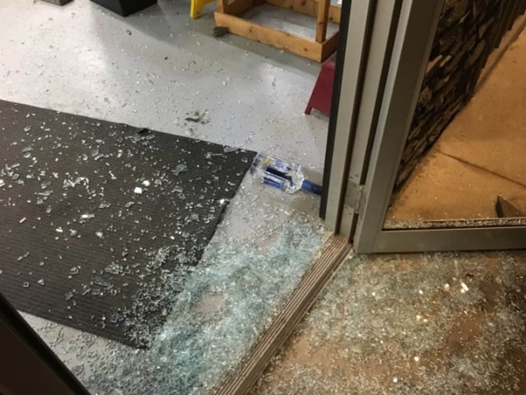 Broken glass on the floor of an entryway after a business had a break-in.